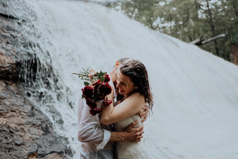 And eloping couple embraces under a waterfall in a rainstorm.