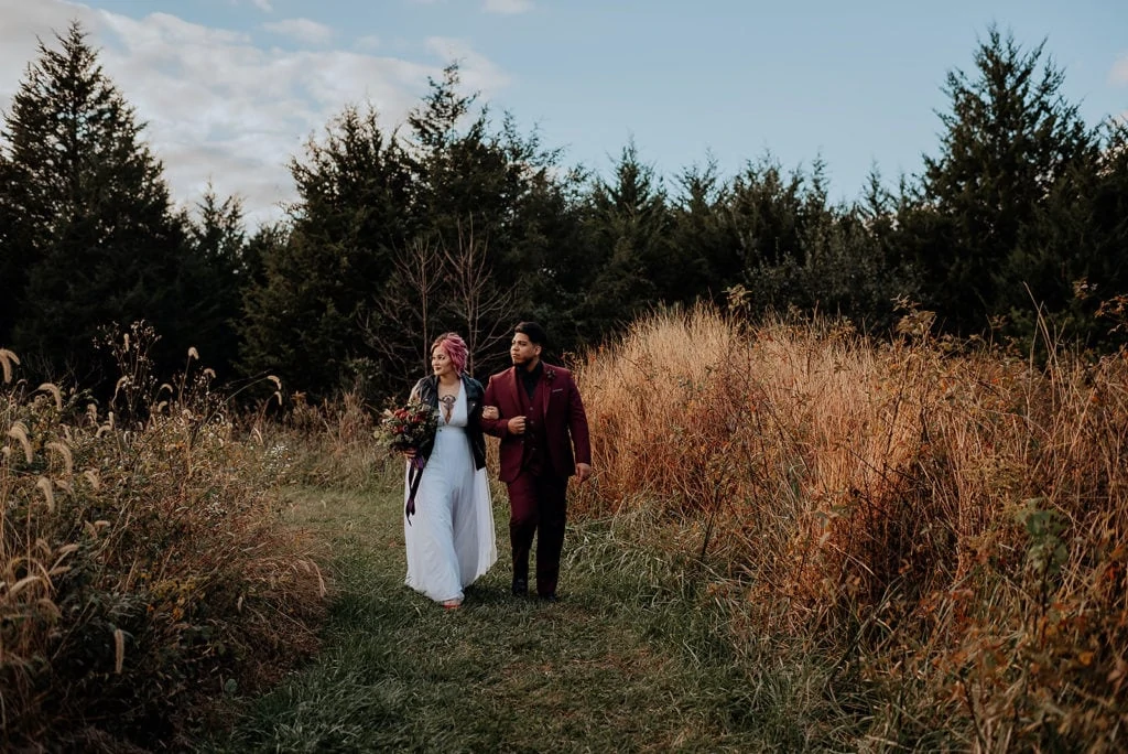 A couple walks through a field for their autumn elopement.