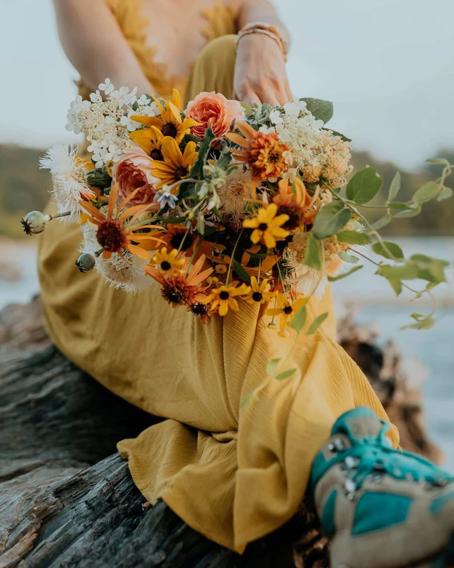 A bride in a yellow dress and vintage hiking boots shows off her bouquet.