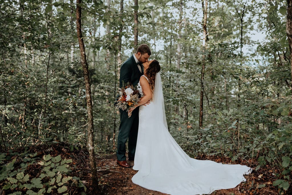 A newly married couple kisses in the forest on their elopement day near Asheville, NC